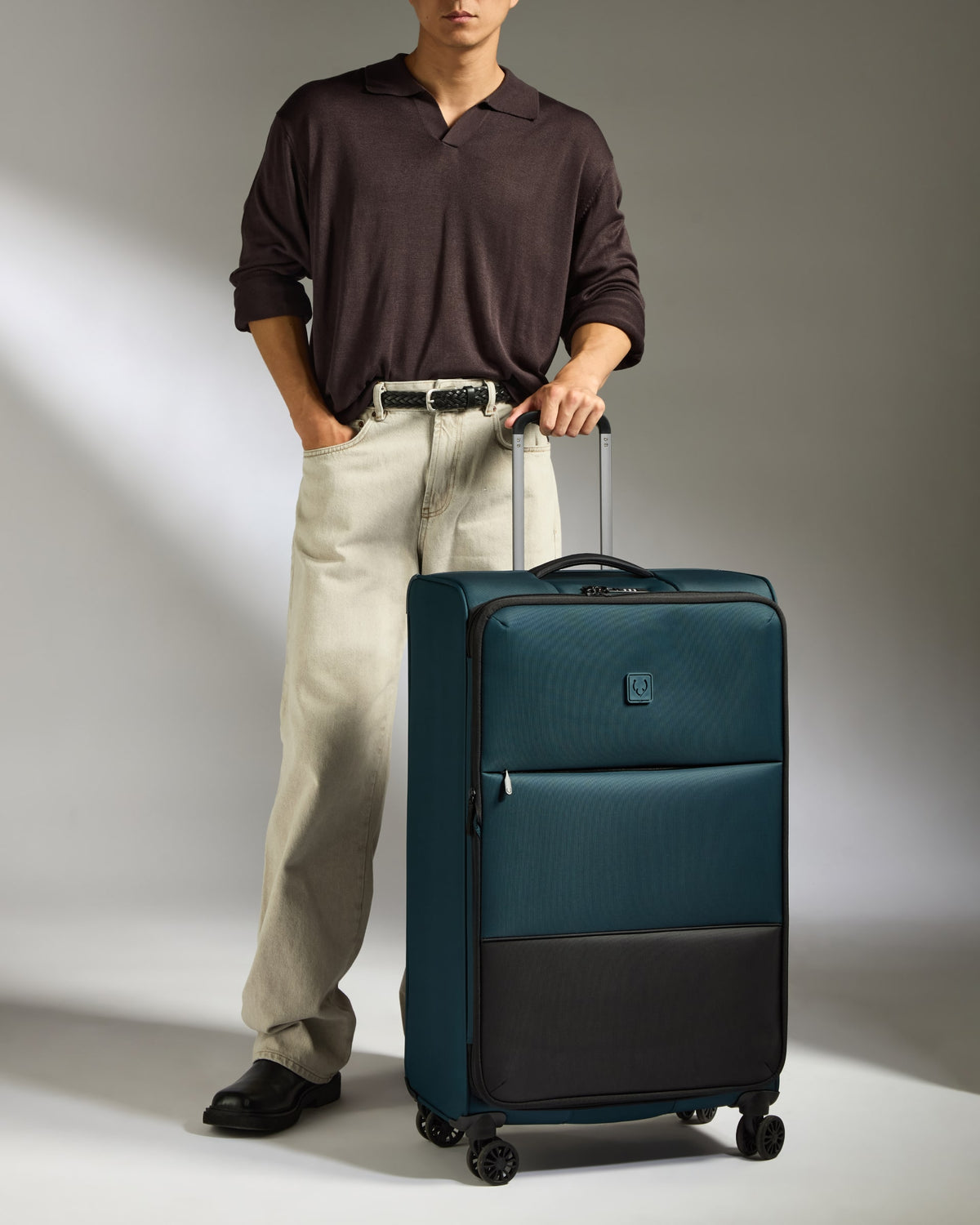 a man standing with his hands in his pockets holding a suitcase