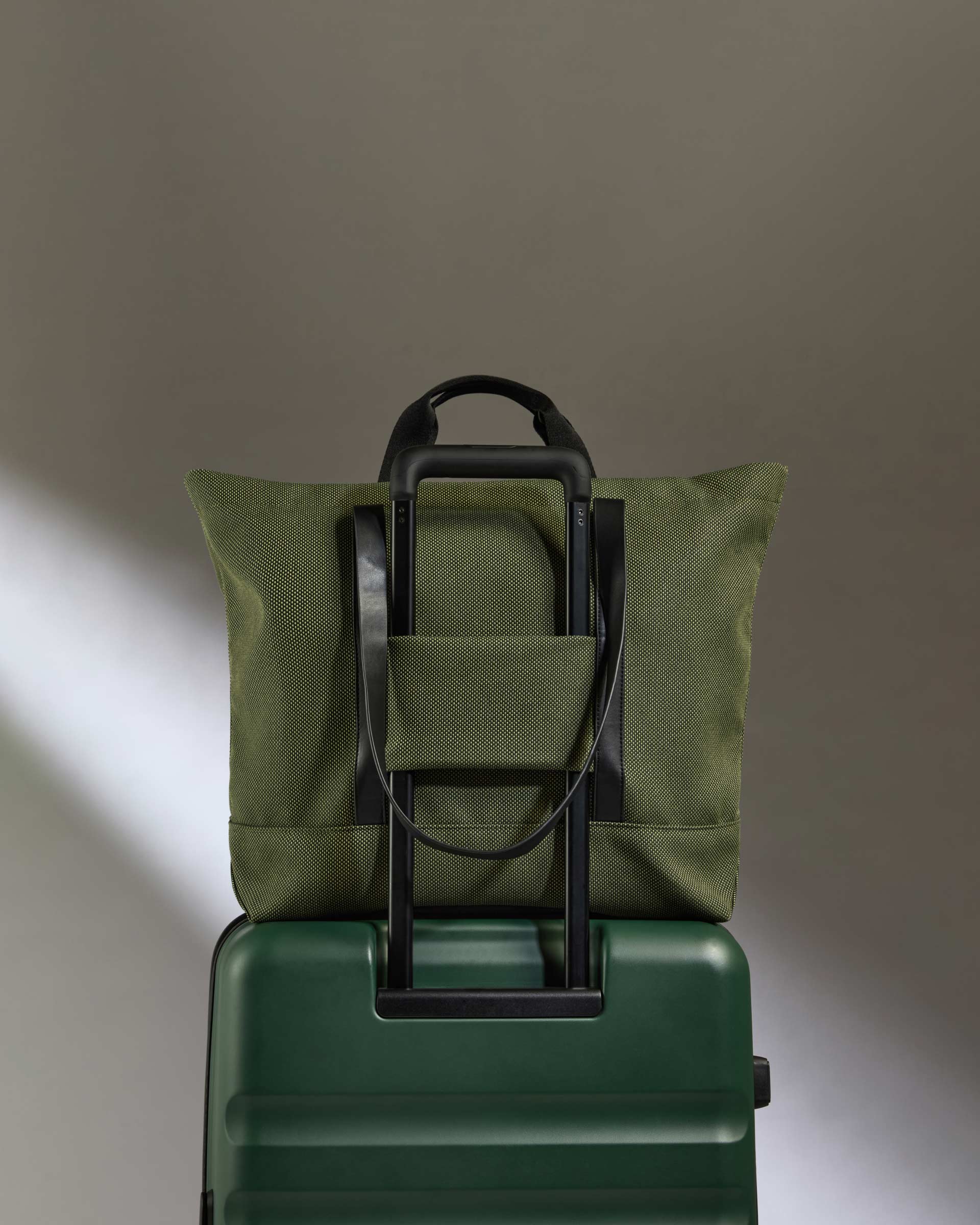 a green bag on top of a green suitcase