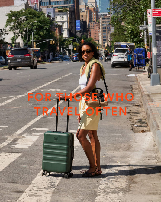 a woman standing on a sidewalk with a suitcase